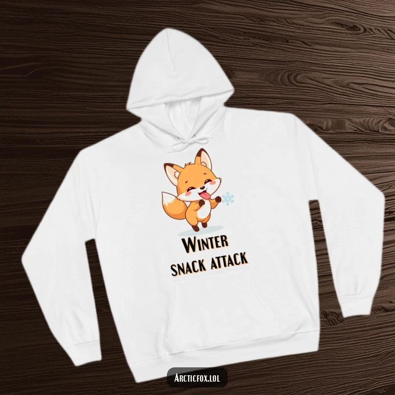 Funny hoodie with a cute fox sticking its tongue out, enthusiastically chasing a snowflake in a joyful winter scene.