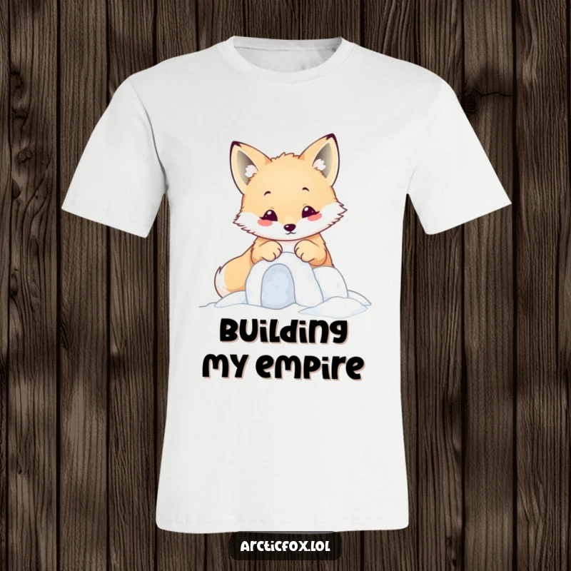 Funny kawaii arctic fox diligently building a tiny snow fort with its paws, featured on a t-shirt.